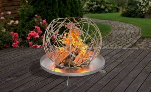 Design-Feuerschale aus unbehandeltem Stahl, fantasievolle kugelförmige Gestaltung und eine stabile runde Bodenplatte auf standsicheren Füßen.